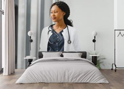 Portrait of female African American doctor standing in her office at clinic Wall mural