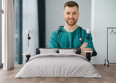 Portrait of smiling doctor looking at camera with arms crossed in medical office Wall mural