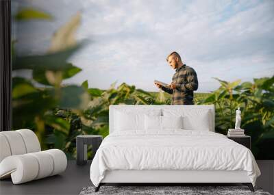 Portrait of young farmer standing in soybean field. Wall mural