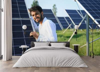 Portrait of Young indian male engineer standing near solar panels, with clear blue sky background, Renewable and clean energy. skill india, copy space. Wall mural