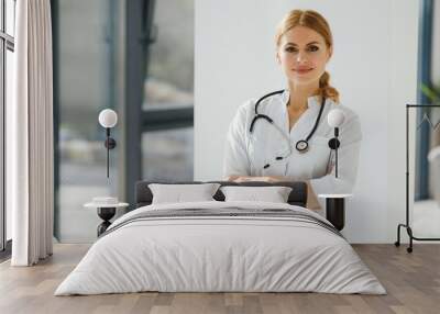 Portrait of young woman doctor with white coat standing in hospital Wall mural