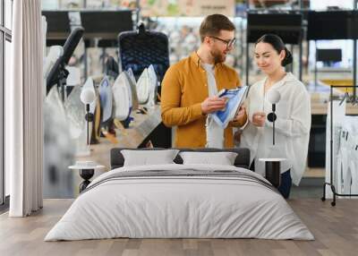 Positive couple chooses iron in store of household appliances Wall mural