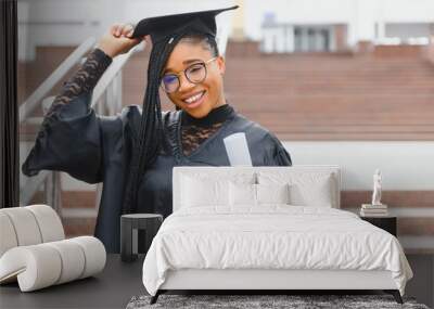 pretty african college student in graduation cap and gown in front of school building Wall mural