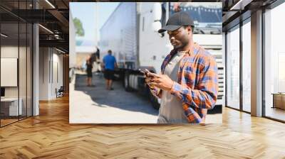 Professional truck driver holding smart phone in front of the trucks Wall mural