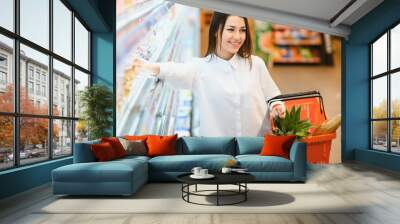 sale, shopping, consumerism and people concept - woman with food basket at grocery store or supermarket Wall mural