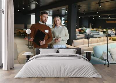 Salesman explaining to woman customer at furniture store Wall mural