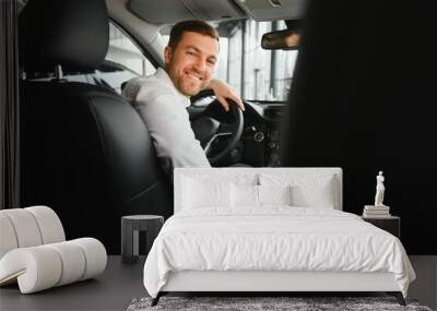 Taxi driver smiling while turning over to the backseat looking talking with clients. Successful businessman husband looking at the backseat at dealer shop before buying a car Wall mural