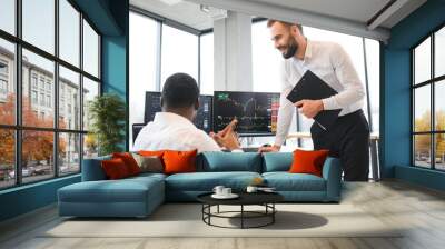 Two confident businessmen, financial analysts or investment advisers sitting at office desk Wall mural