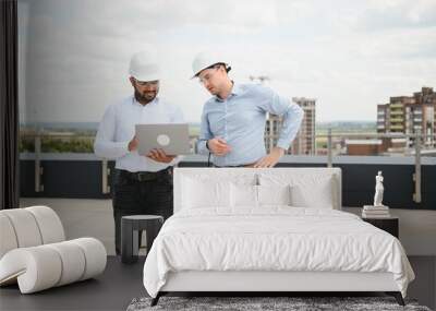 Two multiracial engineer working at site of a large building project. Team of engineer discus at site Wall mural