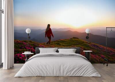 Woman hiker on a top of a mountain. Magic pink rhododendron flowers on summer mountains Wall mural