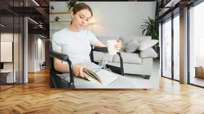 Woman in wheelchair reading book at home Wall mural