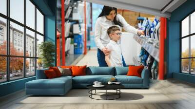 Woman with son choosing electric iron in electronics store Wall mural