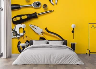 Yellow and black handy tools (pilers and screwdriver) isolated on yellow background Wall mural