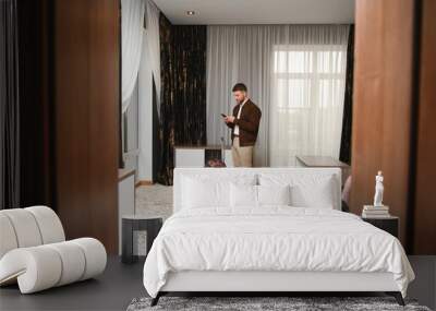 Young businessman with suitcase standing at hotel room. Business trip concept Wall mural