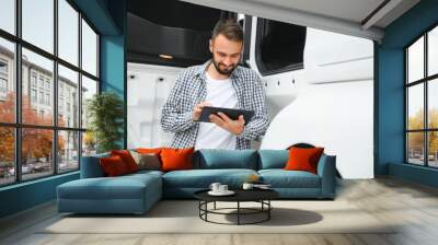 Young handsome truck driver is standing with a tablet near the truck Wall mural