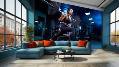 Woman doing squats using barbell in gym. Wall mural