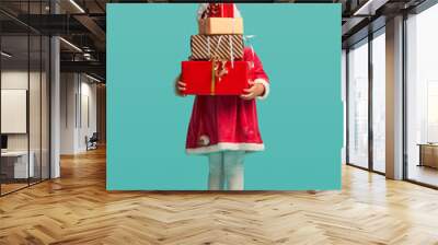 Adorable small baby girl with present box in christmas hat and red dress on the studio background Wall mural