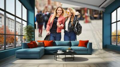 Two girls walking on the city street and talk to each other Wall mural