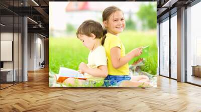 Little girl and boy are reading books outdoors Wall mural