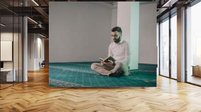 Muslim man praying in mosque and reading Quran Wall mural