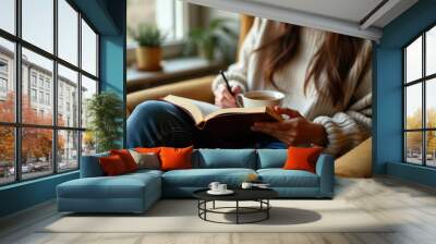 A woman in a cozy beige sweater sits comfortably in a chair, reading a book and holding a cup of tea, beside a window with potted plants and natural light pouring in. Wall mural