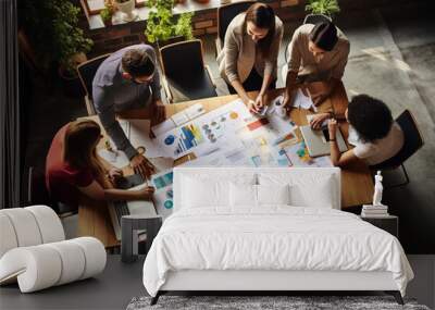 A group of young entrepreneurs in a meeting around a table in an office. View from above. Wall mural