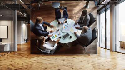 A group of young entrepreneurs in a meeting around a table in an office. View from above. Wall mural