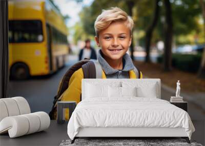 Elementary school student, boy, in front of a yellow school bus. Children are in a hurry to go to school. Wall mural