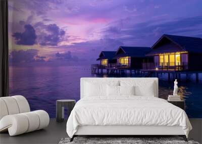 Sunset casts violet hues over the sea surrounding the Maldives bungalows. Wall mural