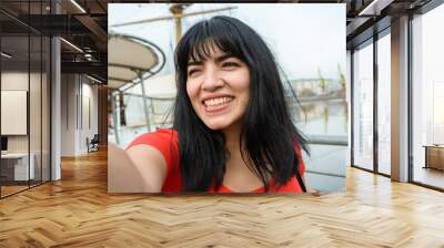 selfie portrait of young latin woman of venezuelan ethnicity dressed in red, smiling happy outdoors Wall mural