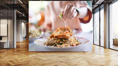 Hand squeeze lemon for cooking food. Pad thai with fresh shrimp and lemon. Wall mural