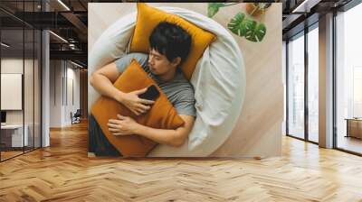 Asian man sleep over the phone on the bean bag sofa, taking a nap in the afternoon. Wall mural