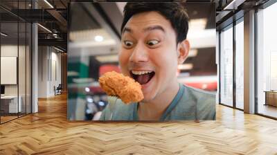 Funny face Asian man eat fried chicken. Wall mural