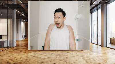 Funny face expression of Asian man try to poop in the toilet. Wall mural