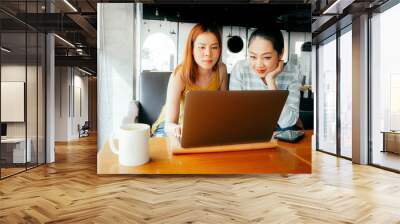 Two girls have some fun checking out the photo work in the laptop in the cafe. Wall mural