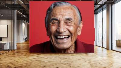 Elderly Latino man with sagging skin laughing light red background Wall mural