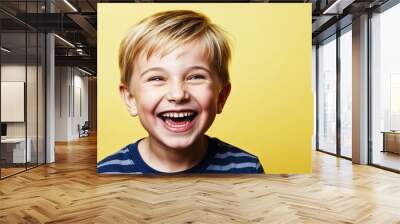 Kid white boy with bright smile and short blonde hair laughing soft yellow background Wall mural