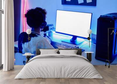 Back view of teenage boy playing video game on PC and streaming live in blue neon light with white screen mockup, copy space Wall mural