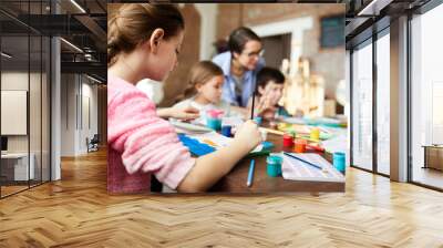 Back view portrait of teenage girl painting picture in art class with group of children, copy space Wall mural