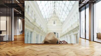 back view portrait of trendy african man wearing hat standing in architectural building with glass r Wall mural