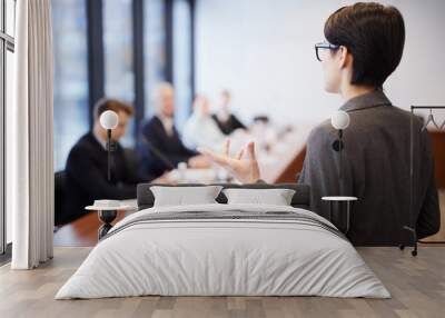 Back view portrait of young businesswoman giving speech in conference room and gesturing, copy space Wall mural