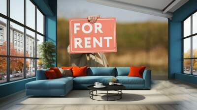 Background image of unrecognizable real estate agent holding red FOR RENT sign while standing in street outdoors, copy space Wall mural