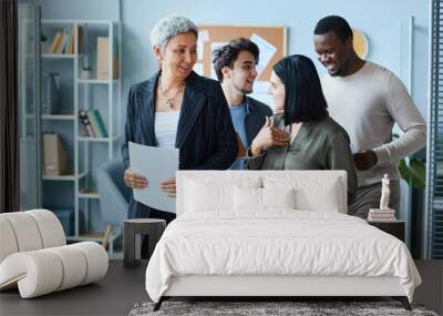 Cheerful multiethnic group of business people with senior female boss walking towards camera in office Wall mural