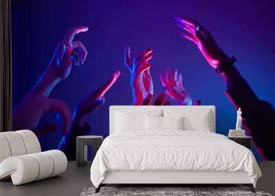 Close up of crowd dancing in club with hands up lit by neon lights, copy space Wall mural