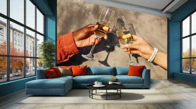 Close-up of two hands clinking champagne glasses during celebration, with shadows cast on wall behind creating an elegant and joyful scene Wall mural