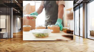 Close up of unrecognizable female worker wearing protective gloves while packaging orders at food delivery service, copy space Wall mural