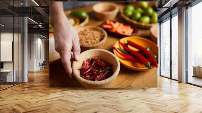 Close up of unrecognizable man holding chili peppers bowl while cooking spicy food, copy space Wall mural