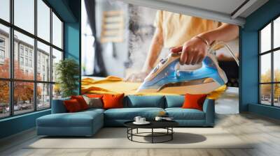 Close up of unrecognizable young woman ironing clothes at home, simple lifestyle and household chores concept, copy space Wall mural