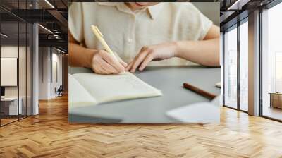 Close up of young girl writing in notebook while studying at home, copy space Wall mural