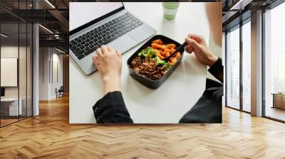 Close up of young woman enjoying healthy lunch with vegetables while using laptop, copy space Wall mural